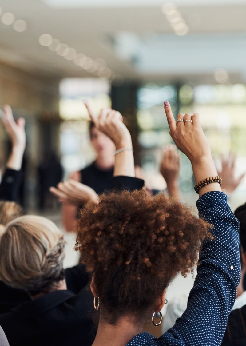 Shot of a group of businesspeople raising their hands to ask questions during a conference